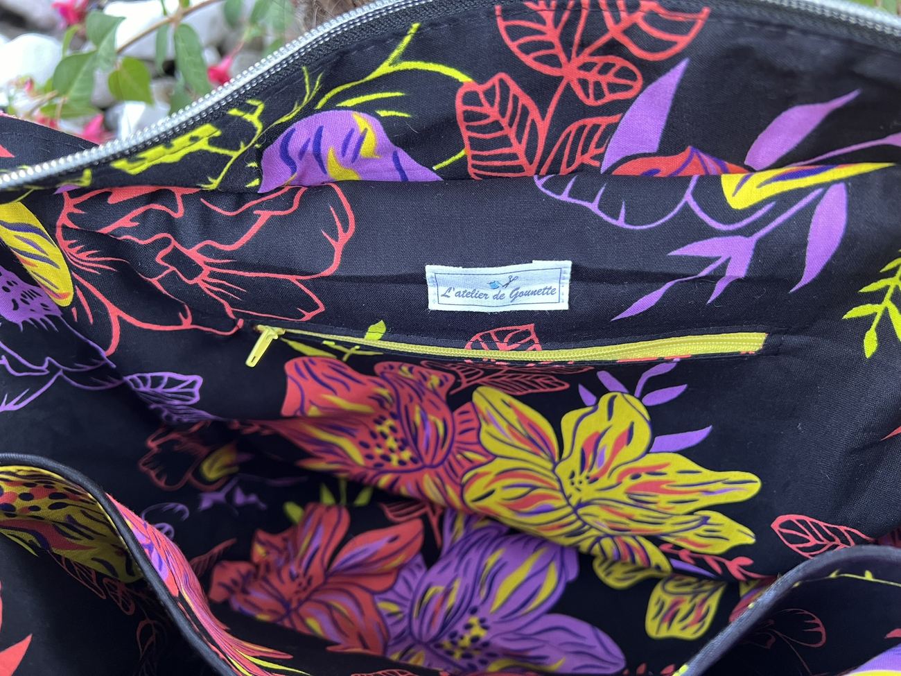 Doublure à grandes fleurs violettes et jaunes d'un sac Kiwana, avec poche zippée et étiquette de l'atelier